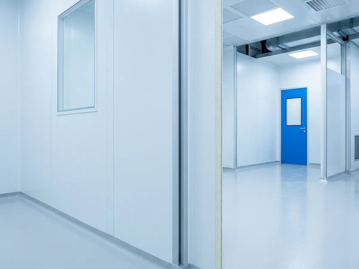 Modular cleanroom wall panels being assembled, showing flush joints and a coved corner profile.
